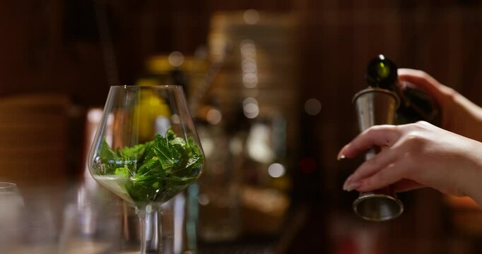 bartender's hand skillfully preparing a refreshing cocktail with mint in a restaurant setting, as the vibrant green mint leaves are muddled for a perfect mojito.