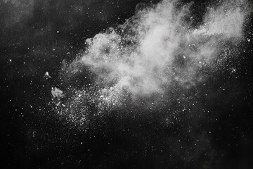 Abstract powder explosion on black background.  A grayscale image displays a cloud of white powder exploding outward against a black backdrop, creating a dynamic and textured effect. 