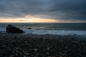 Obraz premium Sunset on a rocky sea beach with clouds