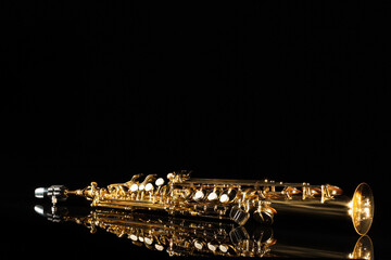 Jazz. One saxophone on mirror surface against black background, space for text