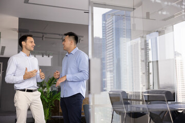 Two positive male business colleagues discussing management process, career, job success, sharing...