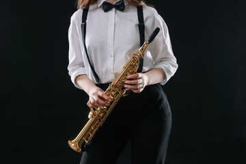 Naklejka premium Musician with soprano saxophone on dark background, closeup