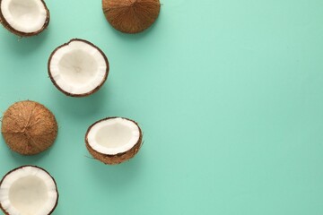 Halves of fresh coconuts on turquoise background, flat lay. Space for text