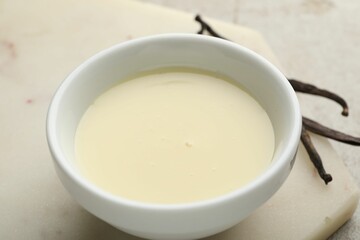 Tasty condensed milk and vanilla pods on light grey table, closeup