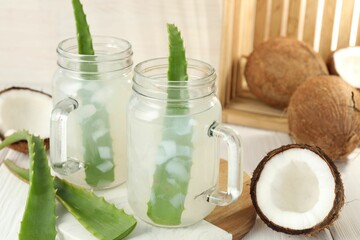 Refreshing drink with coconut and aloe on white wooden table, closeup