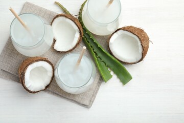 Refreshing drink with coconut and aloe on white table, flat lay