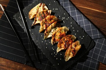 Tasty fried gyoza (dumplings) and chopsticks on wooden table, top view