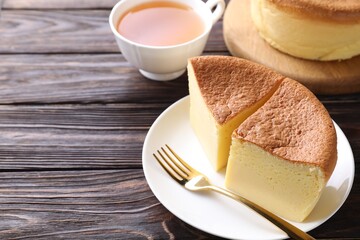 Pieces of tasty Japanese Castella sponge cake, tea and fork on wooden table, closeup. Space for text