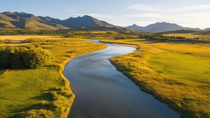 Fototapeta premium Aerial View of a Meandering River in a Lush Green Valley with Mountains
