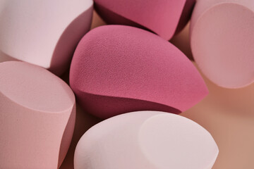 A set of makeup sponges on a pink background.