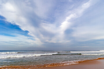 Beautiful landscape with blue sky and soft cirrus clouds over calm Indian Ocean with small foamy waves in Sri Lanka, Asia	