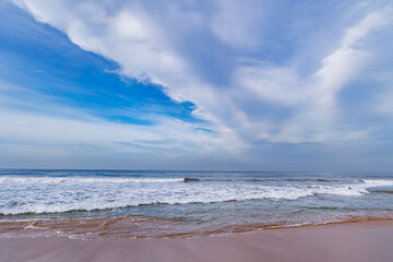 Beautiful landscape with blue sky and soft cirrus clouds over calm Indian Ocean with small foamy waves in Sri Lanka, Asia	