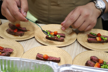 chef experto elaborando aperitivo de carne de solomillo con verduritas y frutos rojos con sus manos y una cucharita