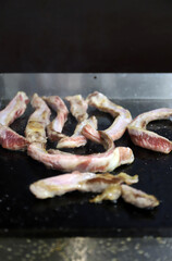 trozos de carne de panceta de cerdo friéndose a ala plancha