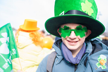 Portrait of a 12 year old boy wearing a green hat and shamrock glasses on St. Patrick's Day.
