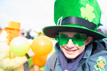 Portrait of a 12 year old boy wearing a green hat and shamrock glasses on St. Patrick's Day.