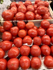 Fresh red tomatoes in container baskets, offered for sale at the supermarket's vegetable stand, showcase organic, vegetarian and healthy food. Close-up