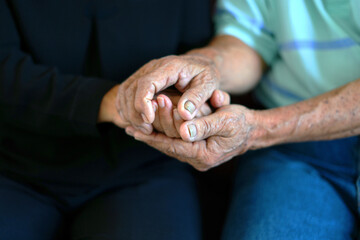 An asian senior couple sitting on sofa, holding hands, old married man supports his wife with mutual understanding, psychological help, comforting, taking care of each other, spreading loves forever.