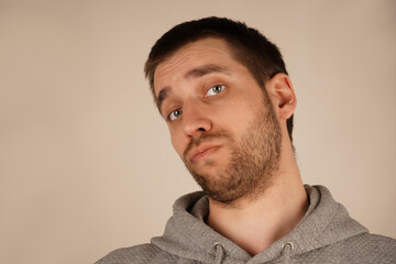 Portrait of a man in a gray hoodie, gazing thoughtfully. His green eyes and trimmed beard add...