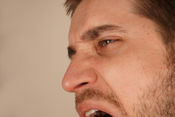 Obraz premium His facial features are tense, clearly expressing his aversion or repulsion to something he finds unpleasant. In this close-up, a young man s face displays a disgusted expression, with his eyes closed