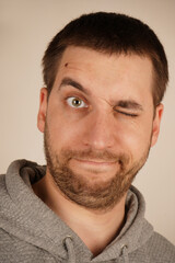 Fototapeta premium In this close-up, a young man s face displays a disgusted expression, with his eyes closed. His facial features are tense, clearly expressing his aversion or repulsion to something he finds unpleasant
