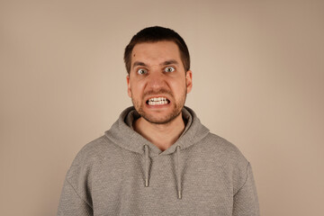 A close-up of a man's face in intense anger, his mouth wide open, showing raw emotion. His...