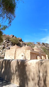 Fujairah, UAE - March 08, 2025: Al Bithnah Fort , Al Bidya Mosque. Traditional Arabic architecture blends seamlessly with the rugged terrain, showcasing the tomb of job under a clear blue sky 