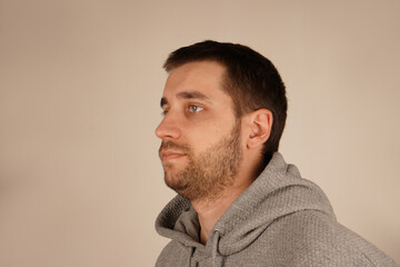 Obraz premium The side view of a man in a grey hoodie highlights his short dark hair and light stubble. His face shows a relaxed demeanor, giving off a casual vibe.