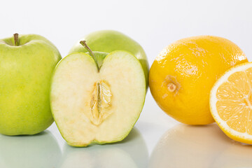 Fresh Green Apples and Juicy Lemons Arranged Beautifully on a Reflective Surface