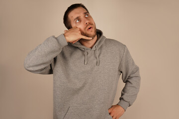 The man positions his hand like a phone near his ear, pretending to make a call. His relaxed demeanor suggests a fun and informal moment. The gesture conveys creativity and humor.