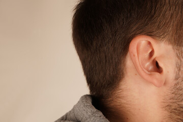 A close-up of a man s ear showcasing its natural lines and skin texture. The image emphasizes...