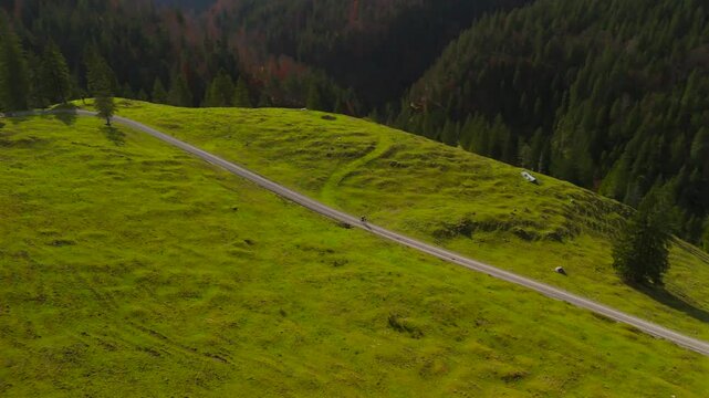 Aerial view of cyclist on gravel bike journey through Valepp Valley in Bavaria, Germany. Riding through Mangfall Mountains and Schlierseer Alps, autumn landscape offers pure adventure and freedom. 