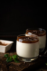 Vanilla panna cotta desert with caramel sause and chocolate in glasses