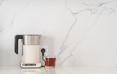 Modern white electric kettle on a white kitchen table
