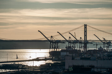Obraz premium Lisbon, Portugal - January 2, 2025: A beautiful view of the iconic 25 de Abril Bridge in Lisbon, Portugal, seen from the Miradouro de Santa Catarina viewpoint.