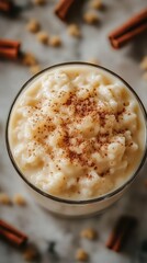 Creamy rice pudding topped with fragrant cinnamon placed on a marble countertop surrounded by spices