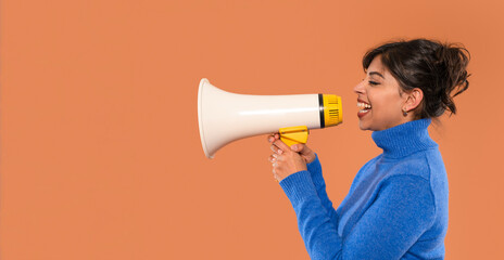 Young woman enthusiastically speaking through a megaphone against a vibrant orange background...