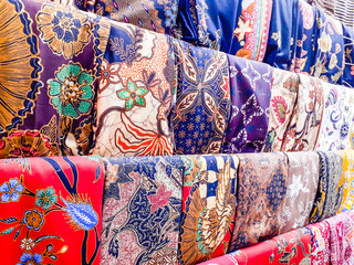 A variety of colors and motifs of batik cloth are displayed in the shop window.
