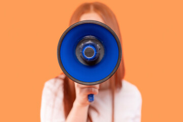 Individual holds a megaphone against a vibrant orange backdrop while promoting a message during a...