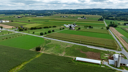 Obraz premium Expansive Farmland With Fields, Silos, and Rural Landscape Under a Cloudy Sky