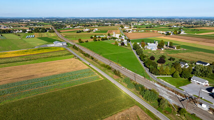 Vast Farmland Stretches Across a Rural Landscape With Fields, Homes, and a Railway in the Distance During Clear Daylight