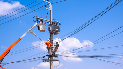 Electricians team with crane truck are working to install electrical equipment on electric power...