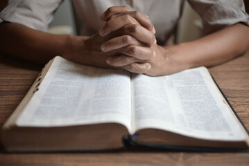 Naklejka premium Man Praying to God with His Bible, Prayer with Reading the Bible on the Wood Table 