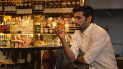 Smart man in white shirt drinking cocktail Old fashioned of special party beverage vibrant waiting for friends or couple at nightclub on Friday meeting night time at luxurious counter bar. Vinosity.