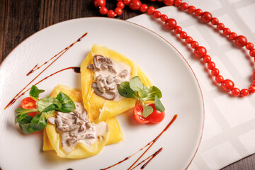 Savory pancakes filled with mushrooms and sour cream, served hot in a rustic restaurant style.