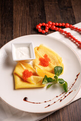 Thin pancakes with red caviar served in a gourmet style. Traditional luxury breakfast or festive appetizer.