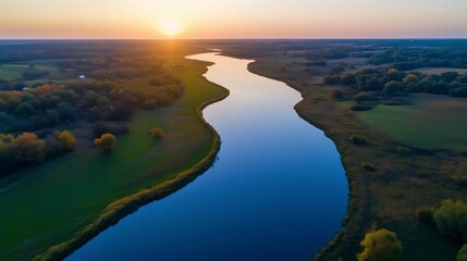 Sunset over a winding river in a rural landscape reflecting warm colors and enhancing the natural beauty of the surroundings