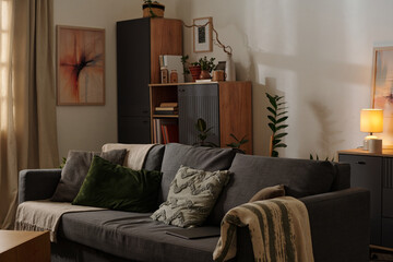 Comfortable living room featuring gray sofa with green pillows, wooden shelving filled with...