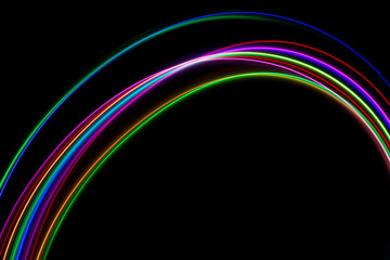A long exposure photograph of colourful lights in a rainbow shape against a black background