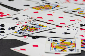 Scattered collection of playing cards, featuring various suits, numbers, and partial card faces. Chaotic arrangement creates a dynamic scene, symbolizing the unpredictability and thrill of card games